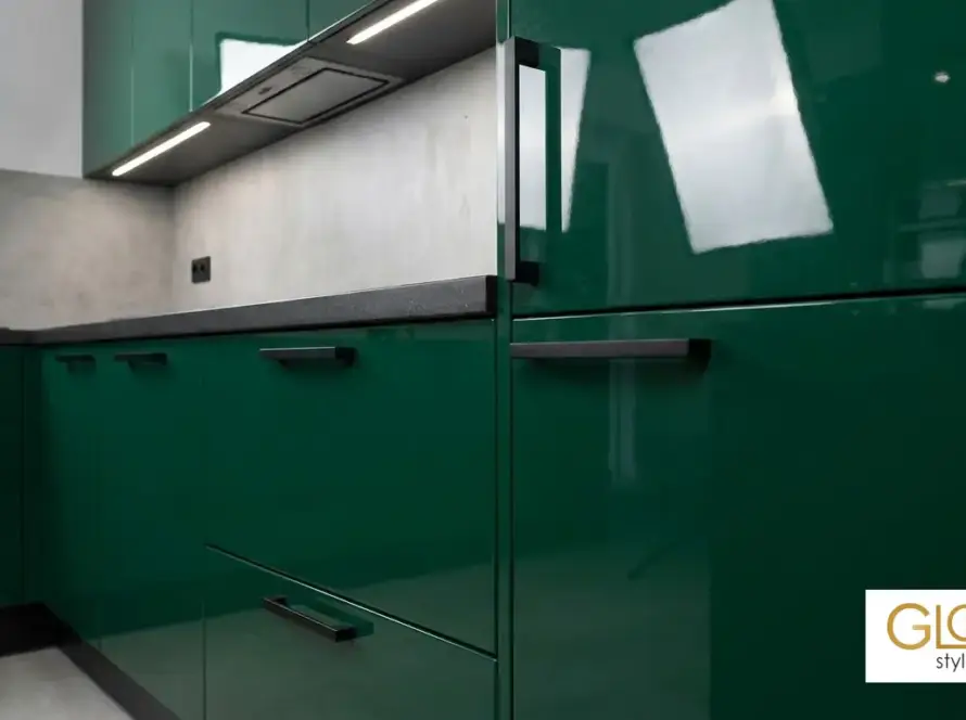 High-gloss green Crysta acrylic sheet kitchen cabinetry with black hardware, showing a glass-like reflective finish